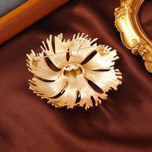 Back view of vintage matte gold floral brooch with pin clasp on brown satin background