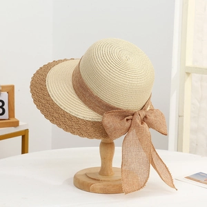 Detailed close-up of woven straw texture and linen bow on beige wide-brim sun hat