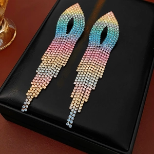 Close-up of rainbow gradient rhinestone tassel earrings on a black leather jewelry box