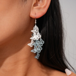 Detail of layered silver and blue gradient hollow butterfly drop earrings on model