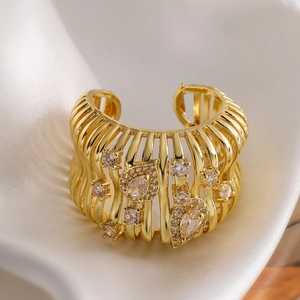 Bague géométrique ajourée dorée avec zircons poires sur tissu en soie blanche