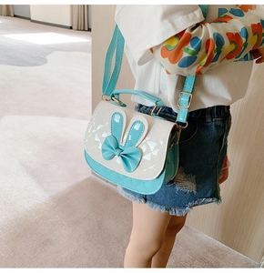 Detail view of blue and white quilted crossbody bag with rabbit ears and bow decoration