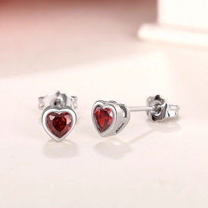 Macro detail of red heart stud earrings with silver metal and secure butterfly backings