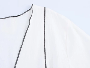 Détail d'un tailleur blanc pour femme avec surpiqûres contrastées noires sur tissu léger