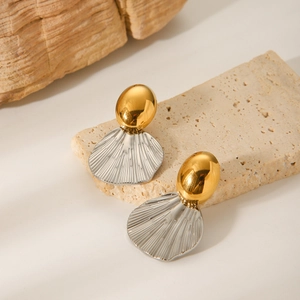 Two-tone oval gold and silver fan-shaped steel earrings on a beige stone surface