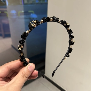 Detailed view of black faceted crystal beads hand-set with gold metal claws on a headband