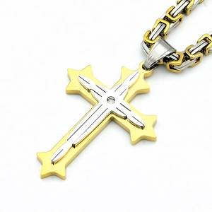 Détail d'un pendentif croix triple bicolore en acier inoxydable avec une chaîne byzantine