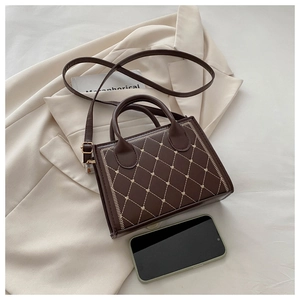 Detailed view of dark brown quilted leather handbag placed on an ivory blazer