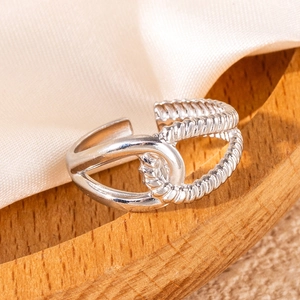 Detailed view of silver hollow leaf ring on wooden tray with white silk fabric