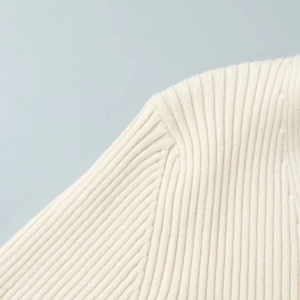 Close-up of vertical ribbed knit texture and shoulder seam on a cream v-neck midi dress