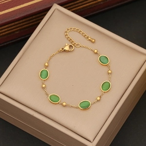 Gold-plated stainless steel bracelet with oval emerald green stones on display