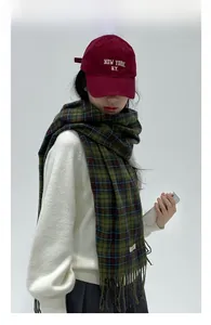Detail of dark green plaid tassel scarf with coarse wool texture worn by a model