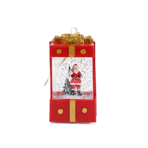 Red Christmas gift box snow globe with Santa Claus figure and gold glitter bow