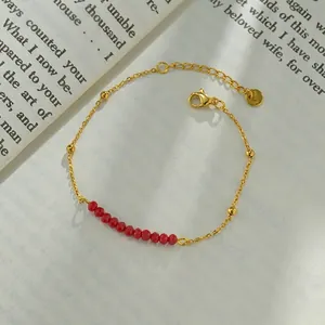 Detail of minimalist gold-plated stainless steel chain with shiny red faceted beads