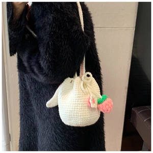 Detail of white handmade crochet bucket bag with strawberry and flower charms