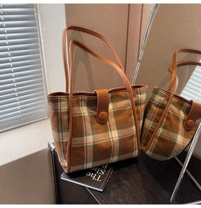 Detail of checkered woolen tote bag with brown leather straps and mirrored reflection