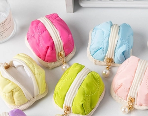 Detailed view of quilted macaron-colored pouches with gold zippers and pearl charms