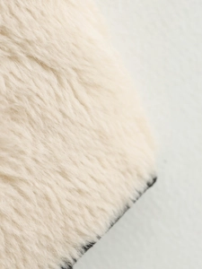 Dettaglio macro della pelliccia sintetica crema e cucitura fine sul cappotto di lana