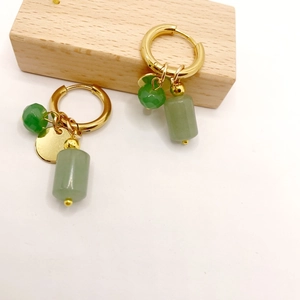 Golden stainless steel hoop earrings with green natural stone pendants on wooden block