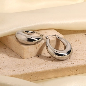 Polished silver teardrop earrings on beige stone and silk backdrop