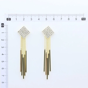 Detailed view of long gold tassel earrings with square crystal studs and scale measurement
