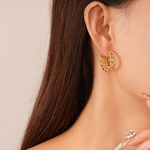 Close-up of golden chain earrings with cubic zirconia stones on female model ear