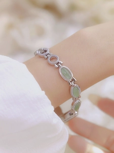 Detail of silver chain watch featuring green jade stones on an elegant braided strap