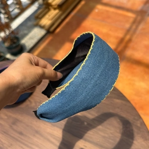 Detail of wide blue denim headband featuring decorative bright yellow hand-stitched edges