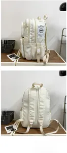 Detail of a cream-colored multi-pocket backpack with durable fabric and side brand label
