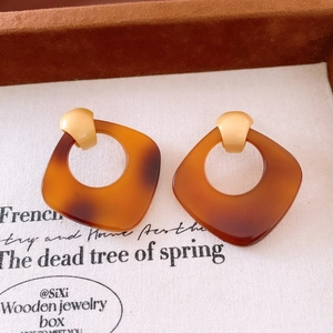 Gros plan de boucles d'oreilles carrées en acétate à motif écaille sur papier vintage