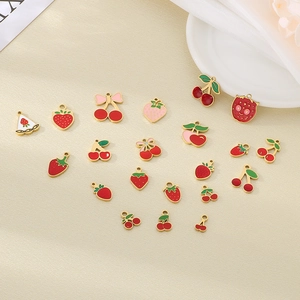 Mix di ciondoli a fragola e ciliegia in smalto su tessuto beige per gioielli fai-da-te