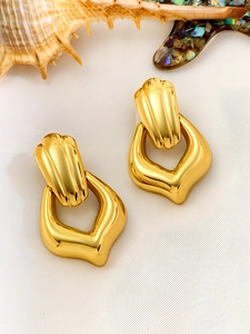 Detailed view of gold geometric vintage earrings on white fabric with seashells