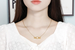 Close-up of golden MOM letter pendant with heart detail on elegant stainless steel chain