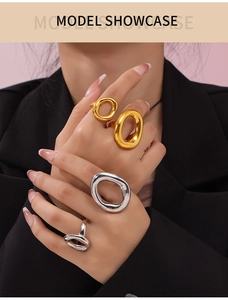 Close-up of minimalist gold and silver hollow oval rings worn with elegant black blazer