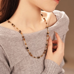 Detail of faux tiger eye beaded necklace with geometric amber beads on a model
