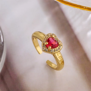 Macro side view of gold heart ring with red zircon and Love engraving detail