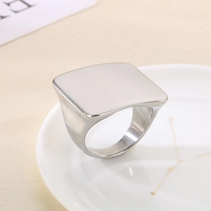 Close-up of polished silver stainless steel square signet ring on a wooden background