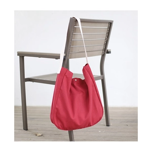 Detail of red canvas crossbody bag hanging on a chair with adjustable shoulder strap
