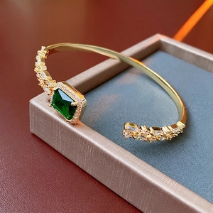 Adjustable gold cuff bracelet with emerald-cut green gemstone and cubic zirconia accents