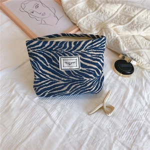 Detail of chenille makeup bag with blue zebra pattern and 'TIME TO PARTY' label