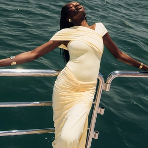 Détail du tissu froncé jaune pâle et de l'épaule asymétrique sur une robe longue ajustée