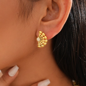 Gros plan de boucles d'oreilles dorées perlées irrégulières avec strass sur un mannequin