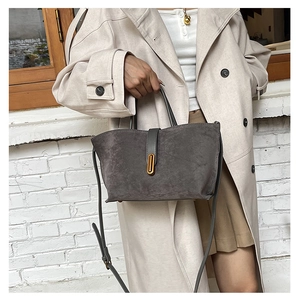 Detail of dark gray matte leather tote with golden vertical lock and adjustable strap