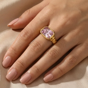 Close-up of a vintage gold-plated twisted ring featuring a large rectangular pink gemstone