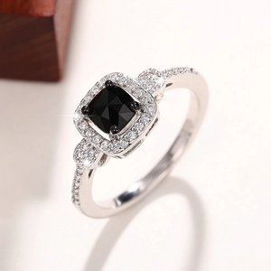 Detailed close-up of a square black gemstone ring with halo diamond setting on a light base