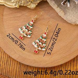 Detailed view of Christmas tree earrings with size measurements on a rustic wood background