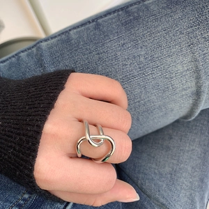 Detail shot of silver twisted metal ring with minimalist knot design worn on hand