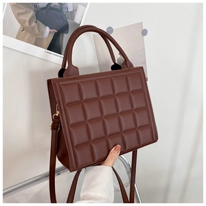 Detail shot of brown quilted texture handbag with elegant top handles and hardware