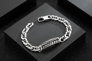 Macro detail of silver wheat chain bracelet with black cross motifs and woven texture