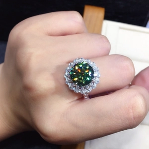 Close-up of sparkling flower-shaped ring with large green moissanite and halo stones